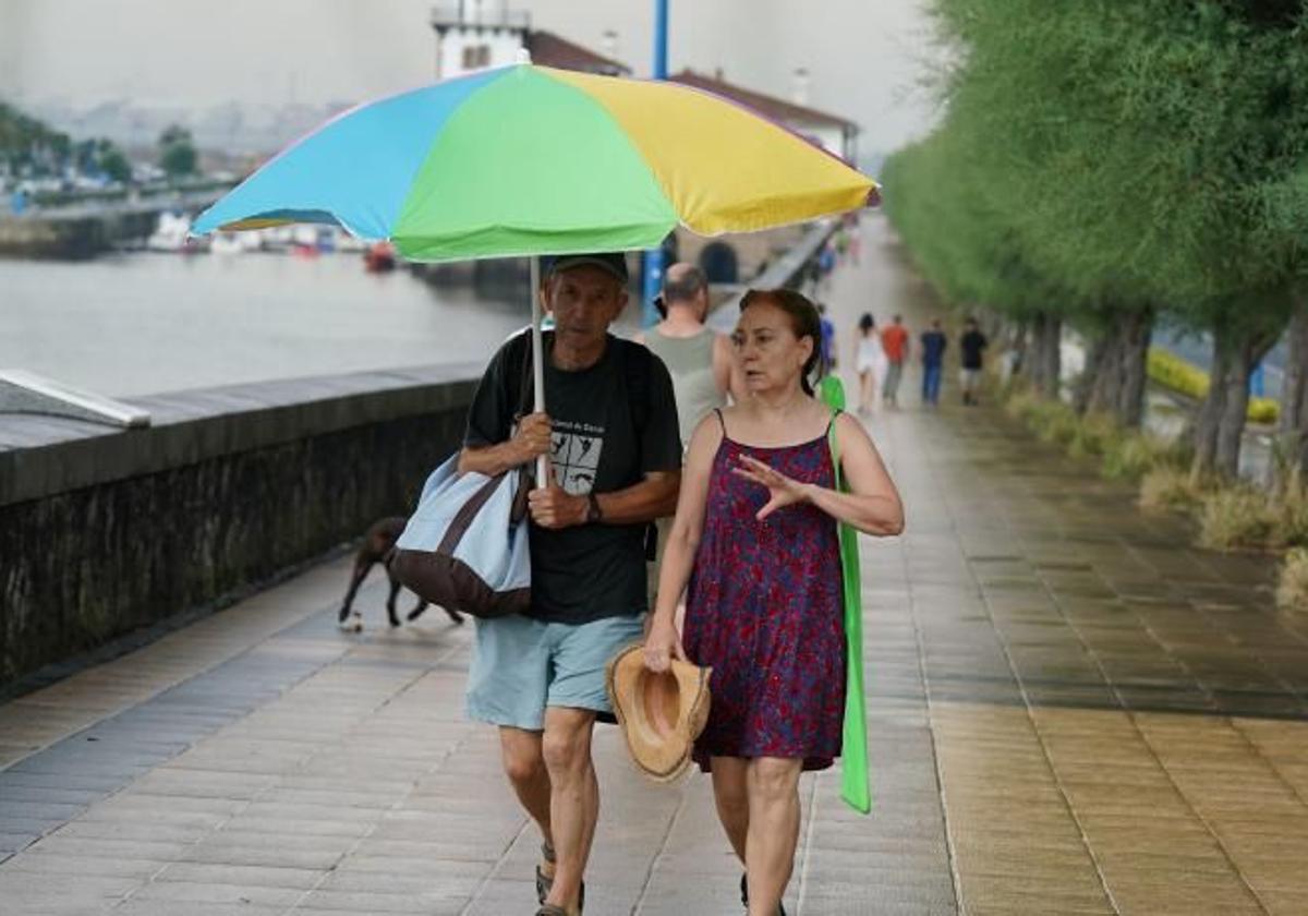 Dos bañistas abandonan la playa por las lluvias.