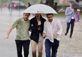 Tres jóvenes se resguardan de la lluvia.