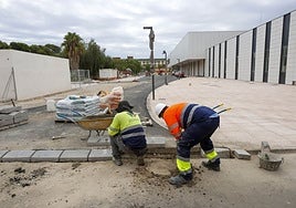 Dos obreros trabajan en la zona exterior del hospital Militar.