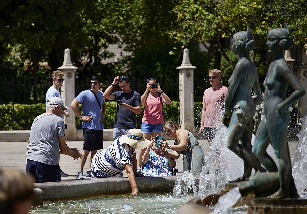 Un grupo se refresca en la fuente de la plaza de la Virgen.