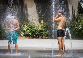 Dos jovenes combaten el calor en una fuente.