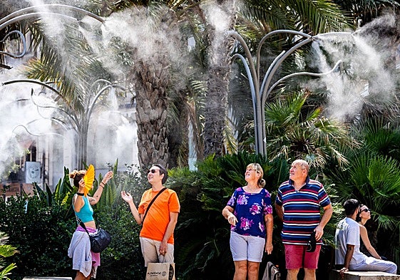 La gente se refresca en los humidificadores de la plaza de la Reina