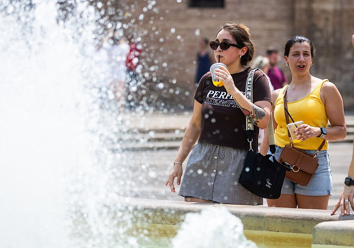 Una mujer se refresca en la plaza de la Virgen, en Valencia.