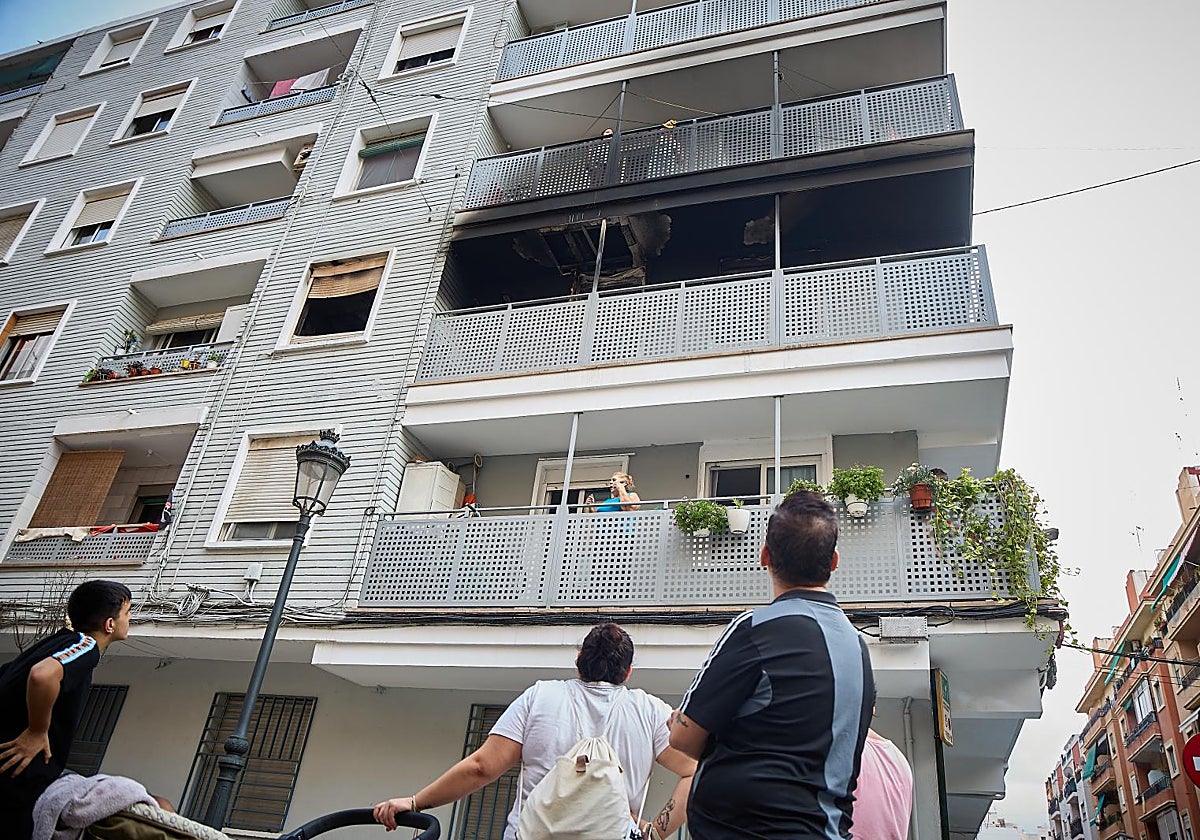 Varios vecinos observan los daños causados por el incendio en la fachada del edificio.