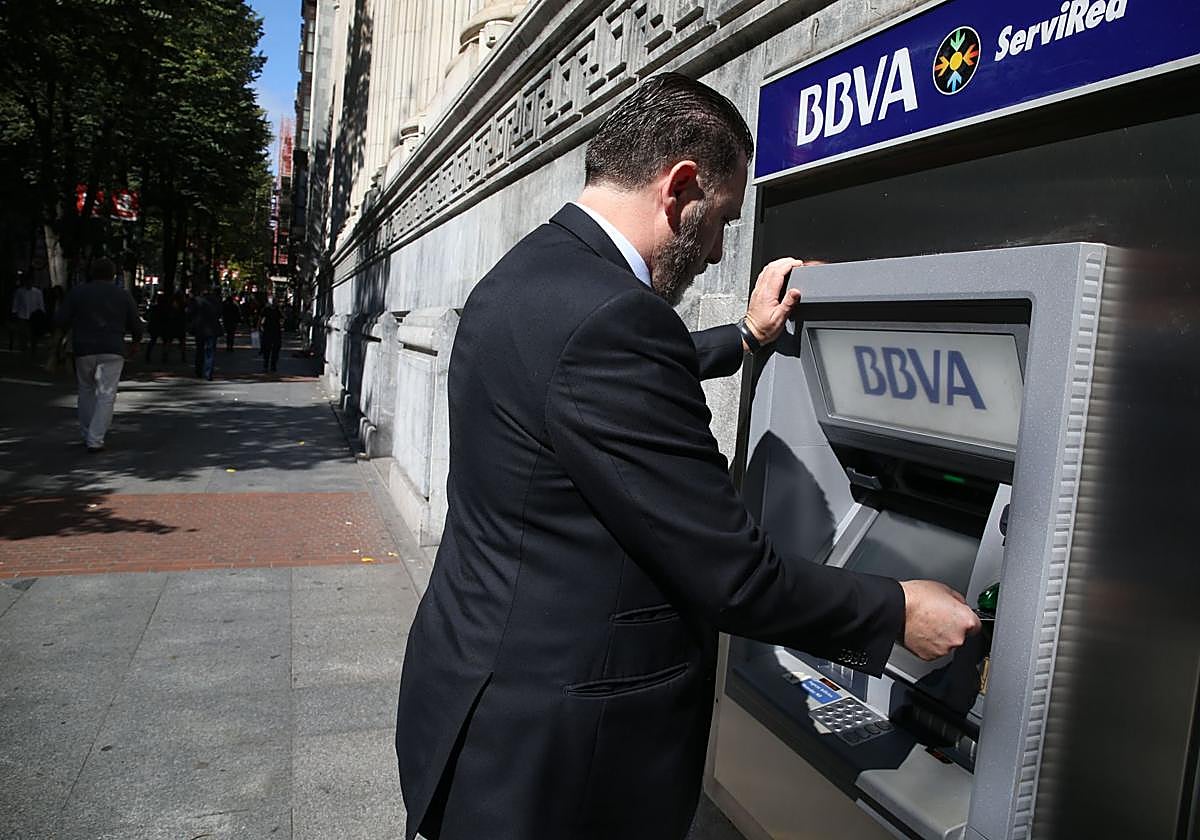 Un hombre realiza operaciones bancarias en un cajero BBVA, imagen de archivo.