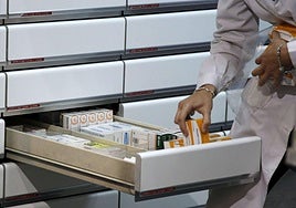 Una farmacéutica escoge un medicamento, imagen de archivo.