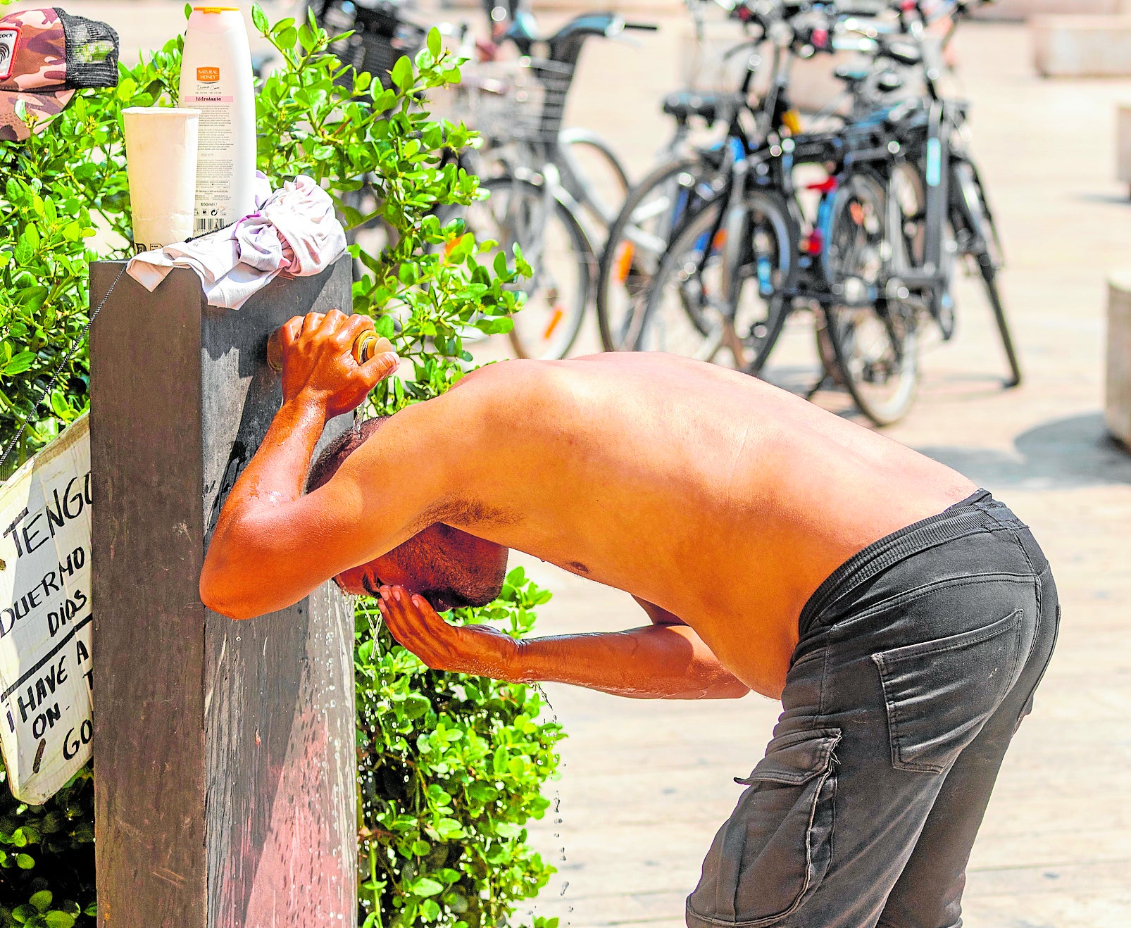 Un hombre se refresca en una fuente del centro de Valencia.