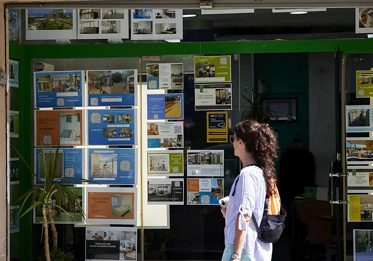 Una joven, ante el escaparate de una inmobiliaria.