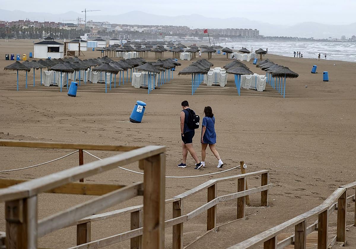 Una pareja se resguarda por los chubascos y tormentas en Valencia.