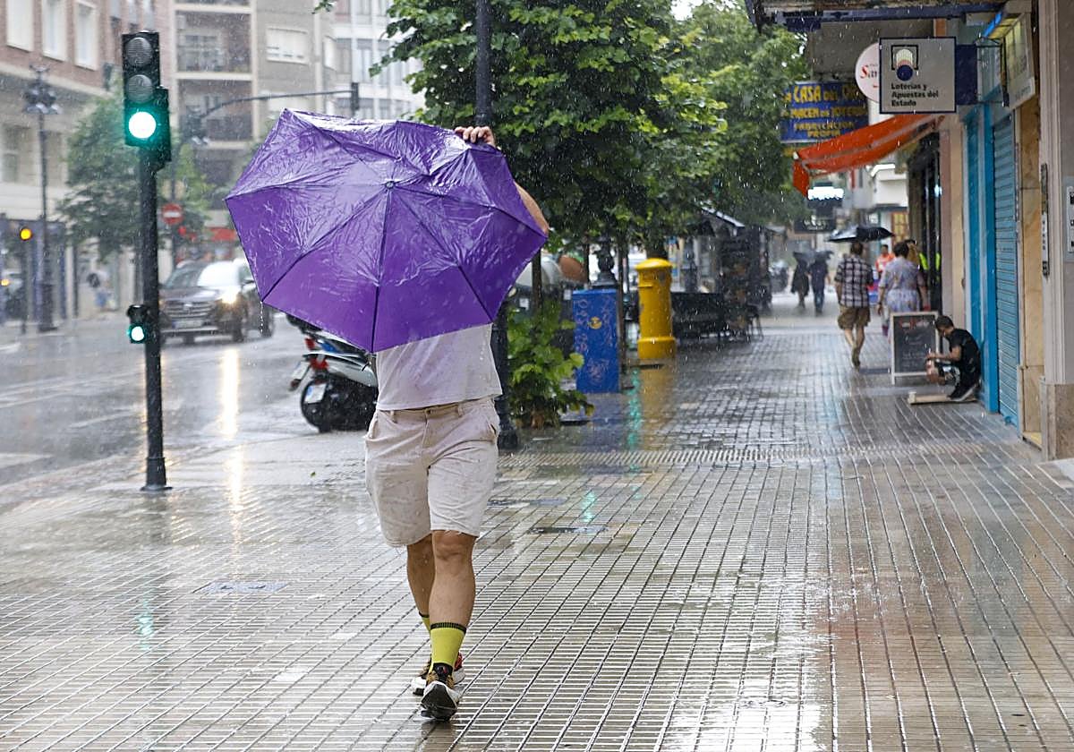 Un hombre se resguarda de las lluvias en Valencia. Imagen de archivo.