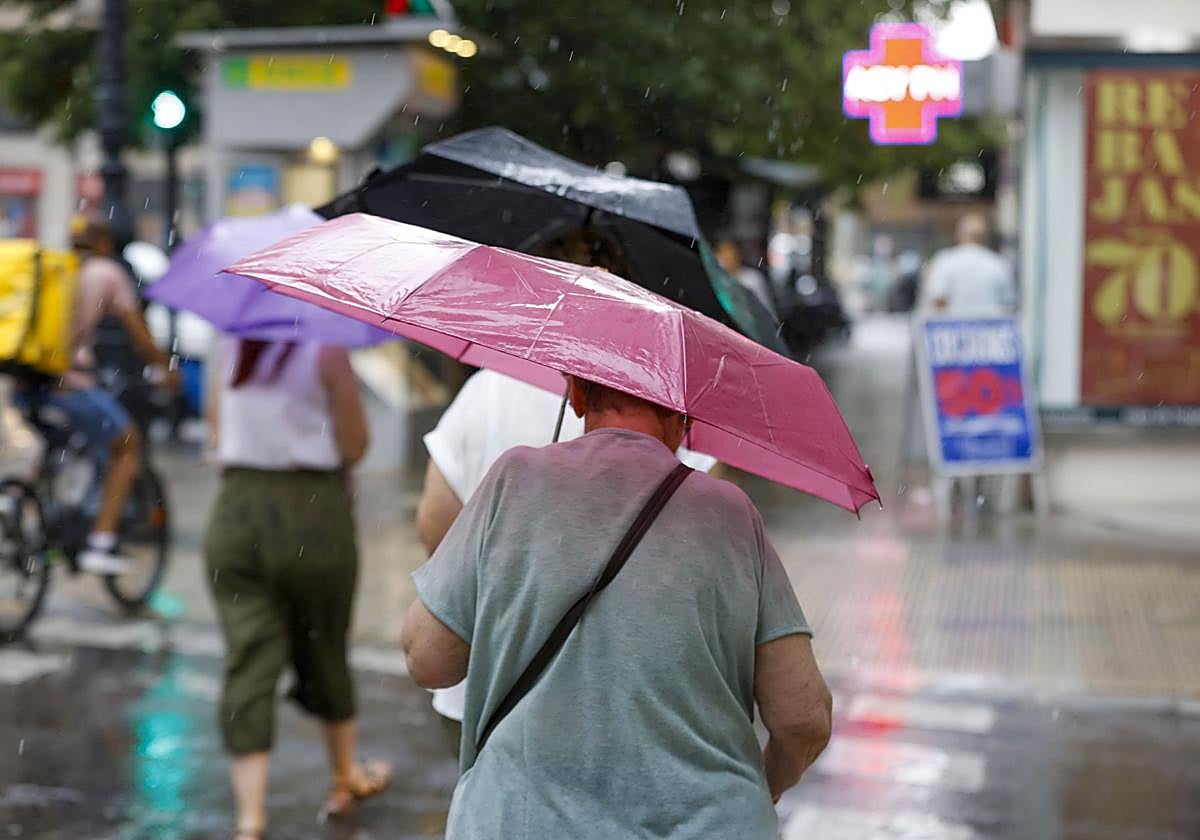 Una mujer se resguarda de las lluvias en Valencia. Imagen de archivo.