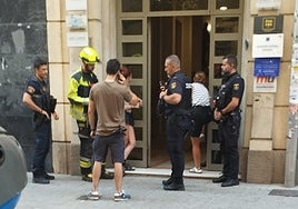 Varios policías y un bombero en la puerta del edificio donde ha ocurrido el suceso.