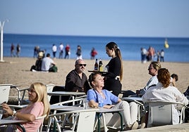 Una camarera sirve en una terraza de la playa de Valencia.