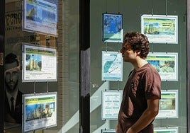 Un joven mira precios de viviendas en una inmobiliaria en Benimaclet.