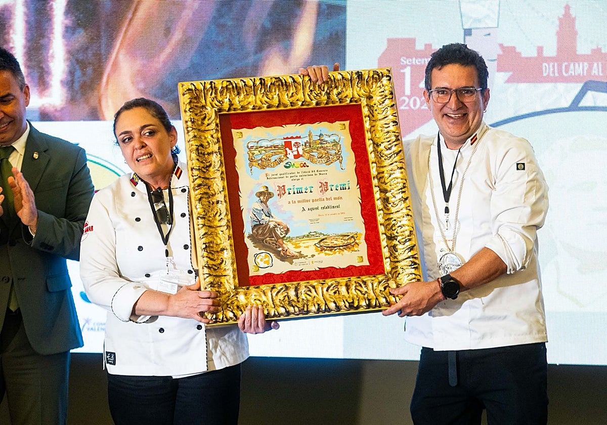 El cocinero ecuatoriano Tomás Angulo y su mujer, Karina Iturralde, muestran el primer premio, este domingo, en el 64 concurso internacional de paellas de Sueca.