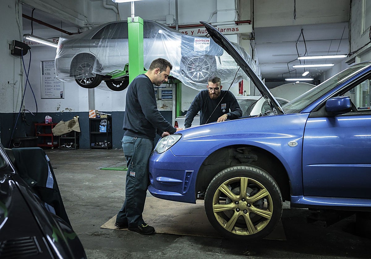 Dos mecánicos trabajan en un taller de automoción.