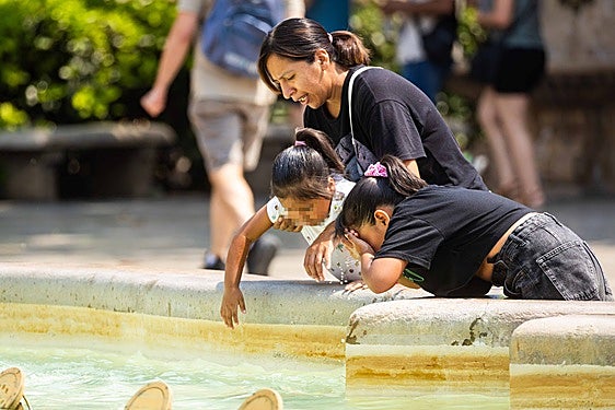 Varias personas se refrescan en una fuente.