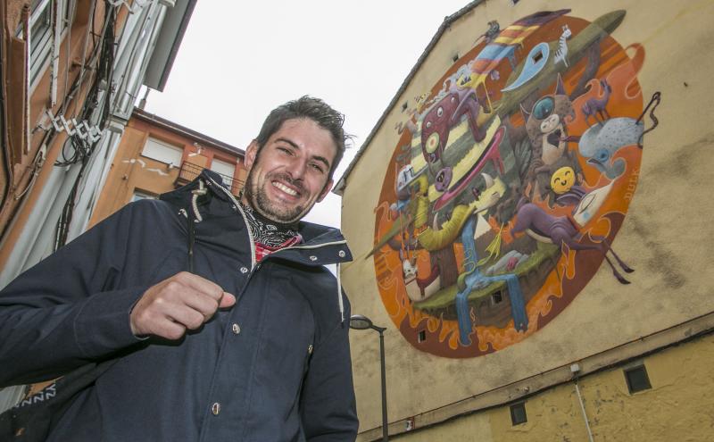 El artista Dulk, junto a uno de sus murales de arte urbano.