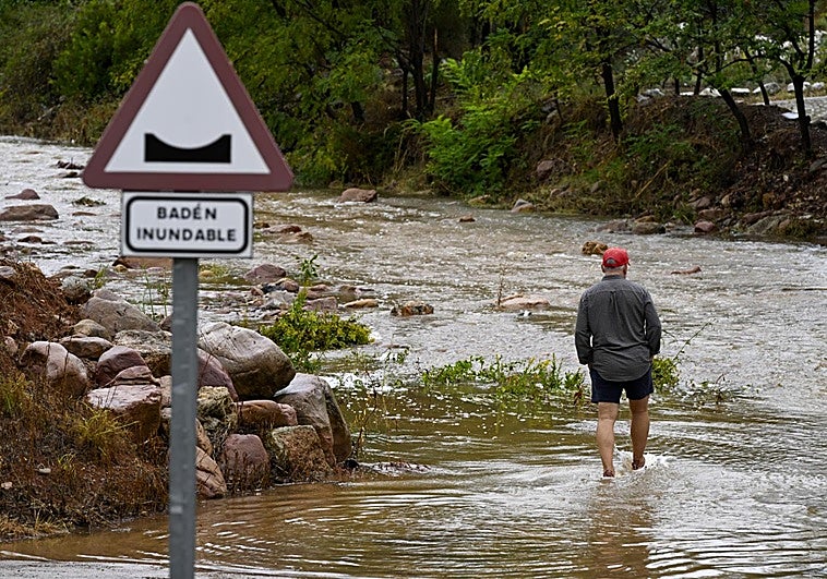 Un hombre trata de cruzar el cauce de una rambla esta mañana.