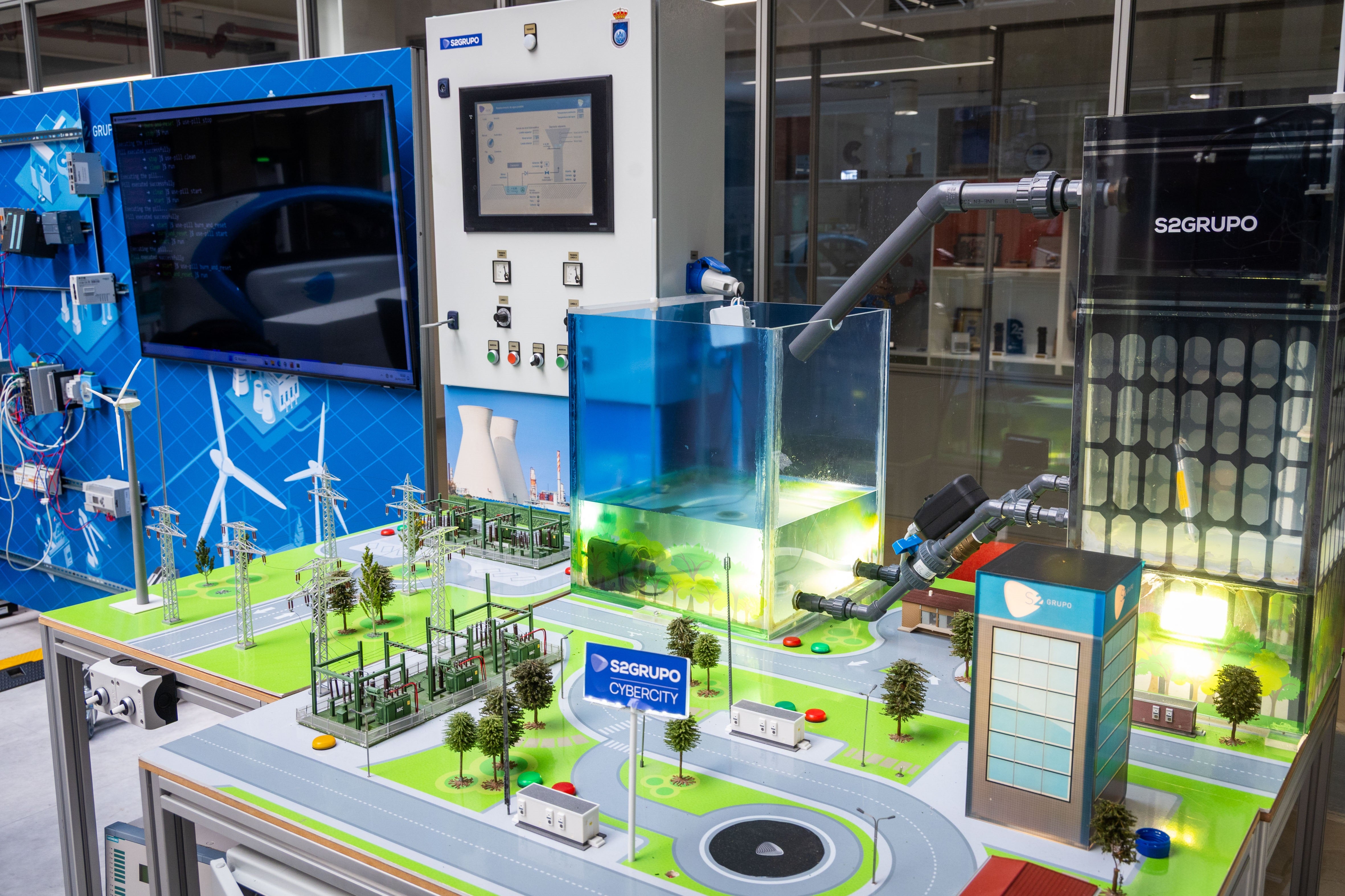 Imagen principal - Arriba, una maqueta de una zona industrial en S2 Grupo con la que simulan ciberataques a plantas potabilizadoras o eléctricas.. Abajo, un cuadro en la sede con el aviso 'el enemigo está escuchando. A la derecha, José Miguel Rosell, CEO de S2 Grupo, durante la entrevista.