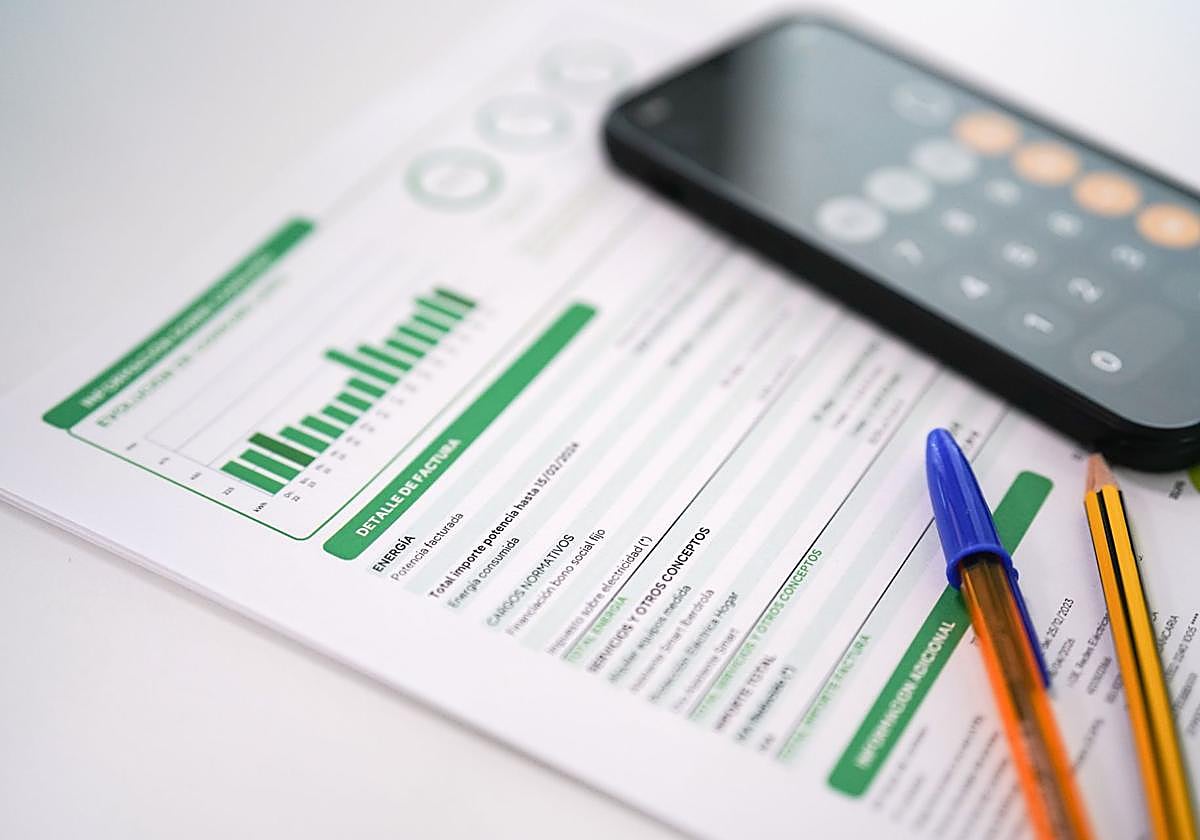 Una factura de la luz junto a un móvil.