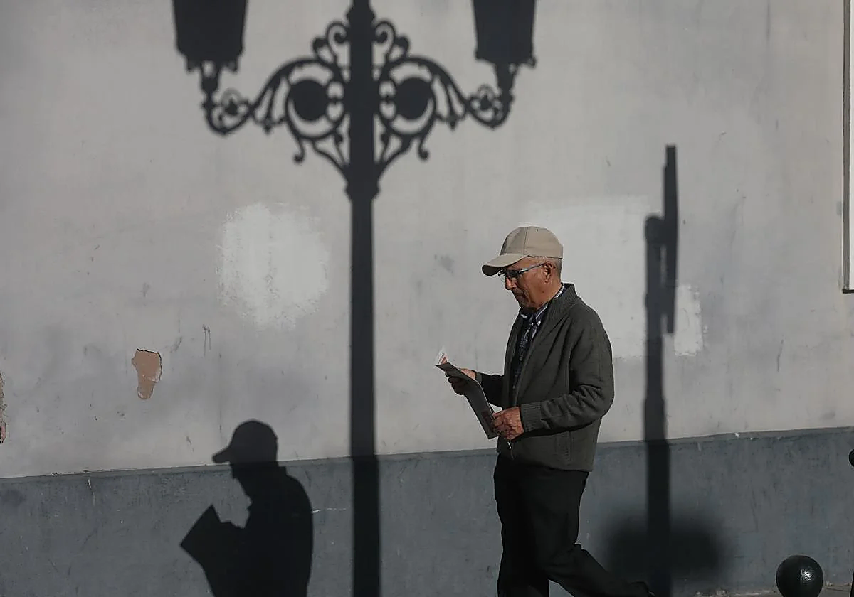 Hombre jubilado pasea por la calle con periódico en mano.