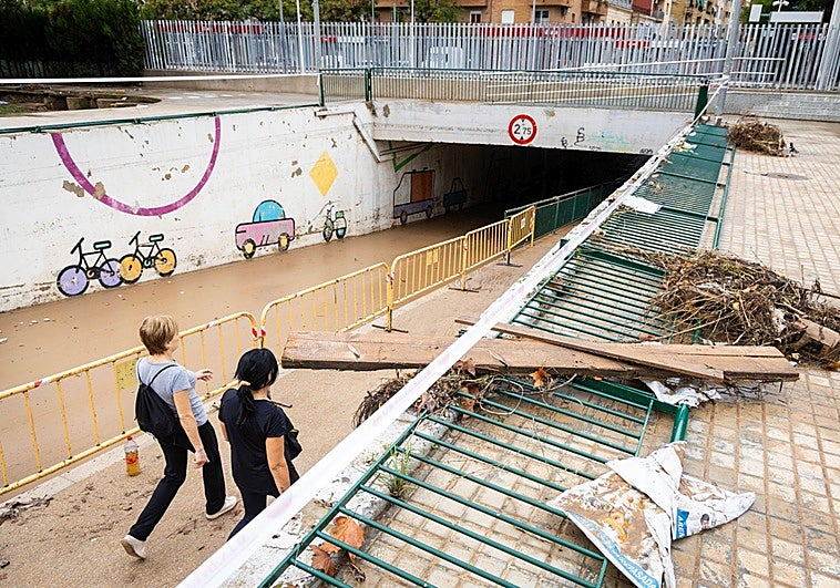 Dos vecinas cruzan el paso inundable lleno de barro en Aldaia, el 12 de octubre de 2025.