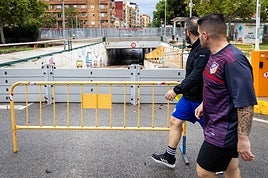 Dos jóvenes pasan este domingo ante un paso inferior inundado en Aldaia.