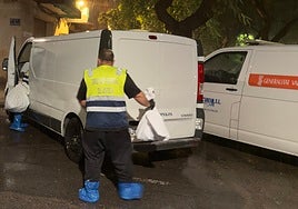 Dos empleados del retén fúnebre introducen en el furgón dos bolsas con los huesos humanos en la calle Luis Fenollet.