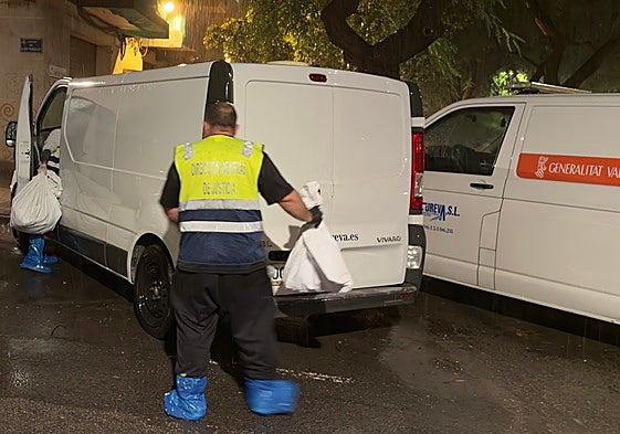 Dos empleados del retén fúnebre introducen en el furgón dos bolsas con los huesos humanos en la calle Luis Fenollet.