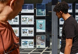 Dos personas observan los precios en una inmobiliaria de Valencia