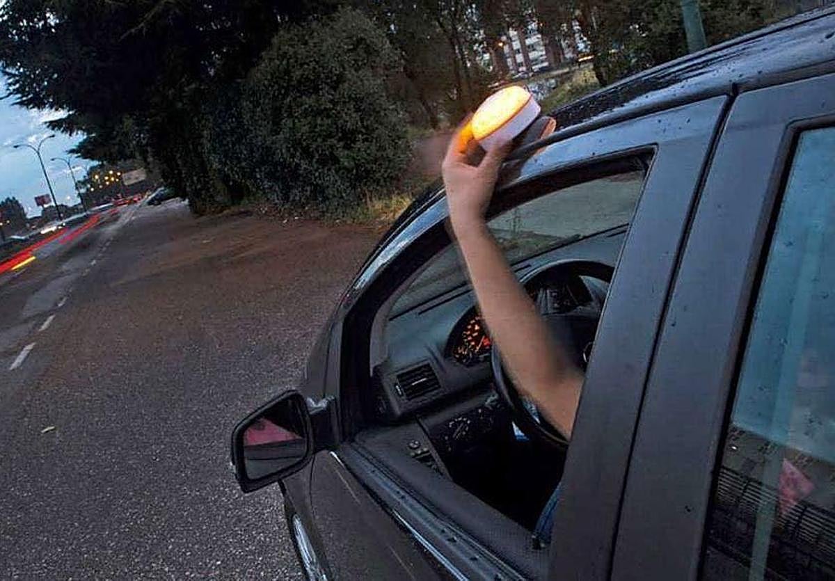 Un conductor coloca una baliza V16 en la parte superior del vehículo.