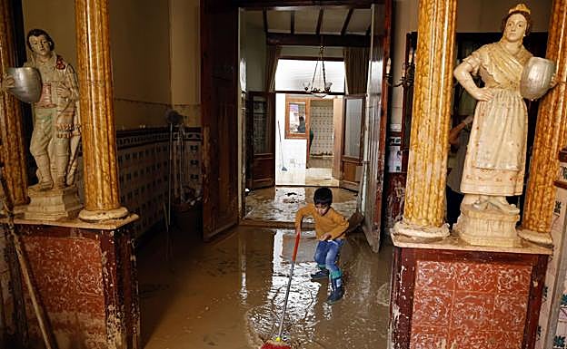 Juan, el hijo de una de las cuidadoras de Pura, limpiando barro tras la dana en la casa de la anciana, y que sólo ha visto en imágenes.