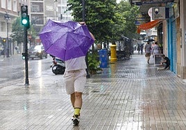 Un hombre se resguarda de la lluvia en Valencia. Imagen de archivo.