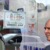 Una administración de Loterías y Apuestas del Estado cuelga el cartel de un premio.
