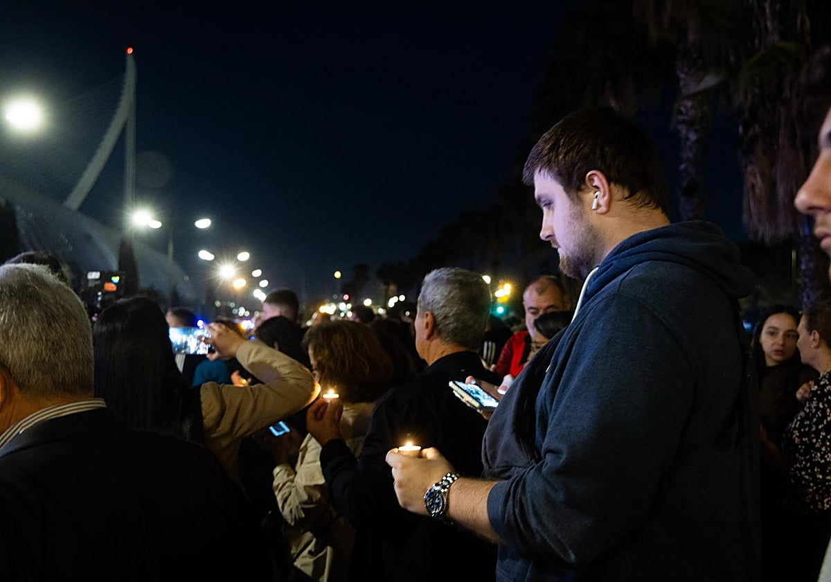 Manifestantes sostienen velas en honor de las víctimas junto a la Ciutat de les Arts.