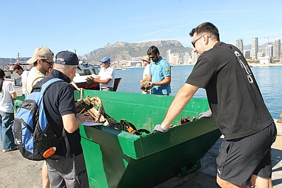 Vluntariado junto a un contenedor con residuos.