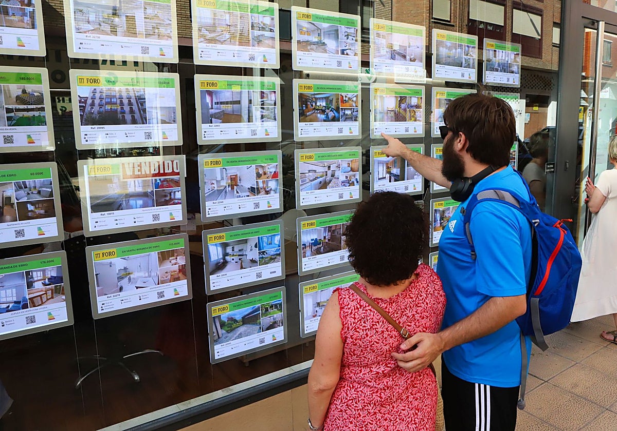 Una pareja consulta los anuncios de una agencia inmobiliaria