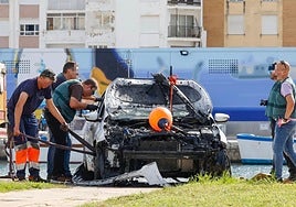 La Guardia Civil analiza el vehículo siniestrado tras sacarlo del agua en el puerto de Gandia.