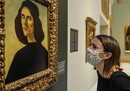 Una mujer mira atentamente un cuadro en un museo.