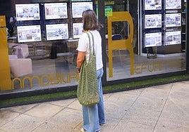 Una mujer consulta la oferta en una inmobiliaria.