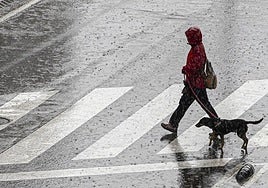 Una mujer cruza una calle durante una tormenta.