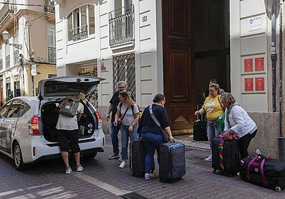 Un grupo de turistas descarga sus maletas a la entrada de un céntrico edificio de Valencia
