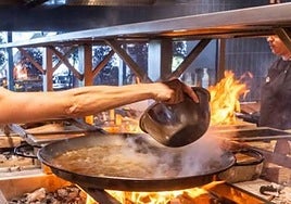Una comensal echa el arroz a una paella en Poble Nou.