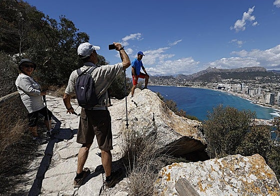 Dos senderistas disfrutan de la estampa del Mediterráneo que se puede observar desde el Penyal d'Ifac.