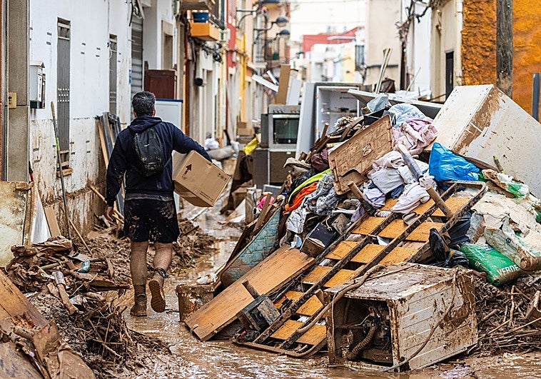 Un hombre recoge escombros en una calle de Algemesí, los días posteriores a la dana de octubre de 2024.