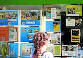 Una potencial compradora observa el escaparate de una inmobiliaria.