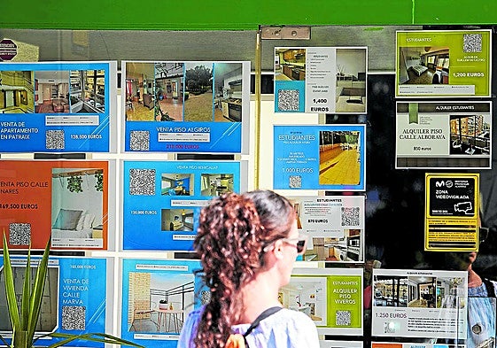 Una potencial compradora observa el escaparate de una inmobiliaria.