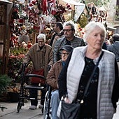Varias personas pasean por un mercadillo navideño.