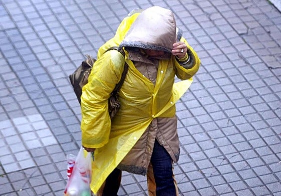 Una mujer pasea abrigada por la calle.
